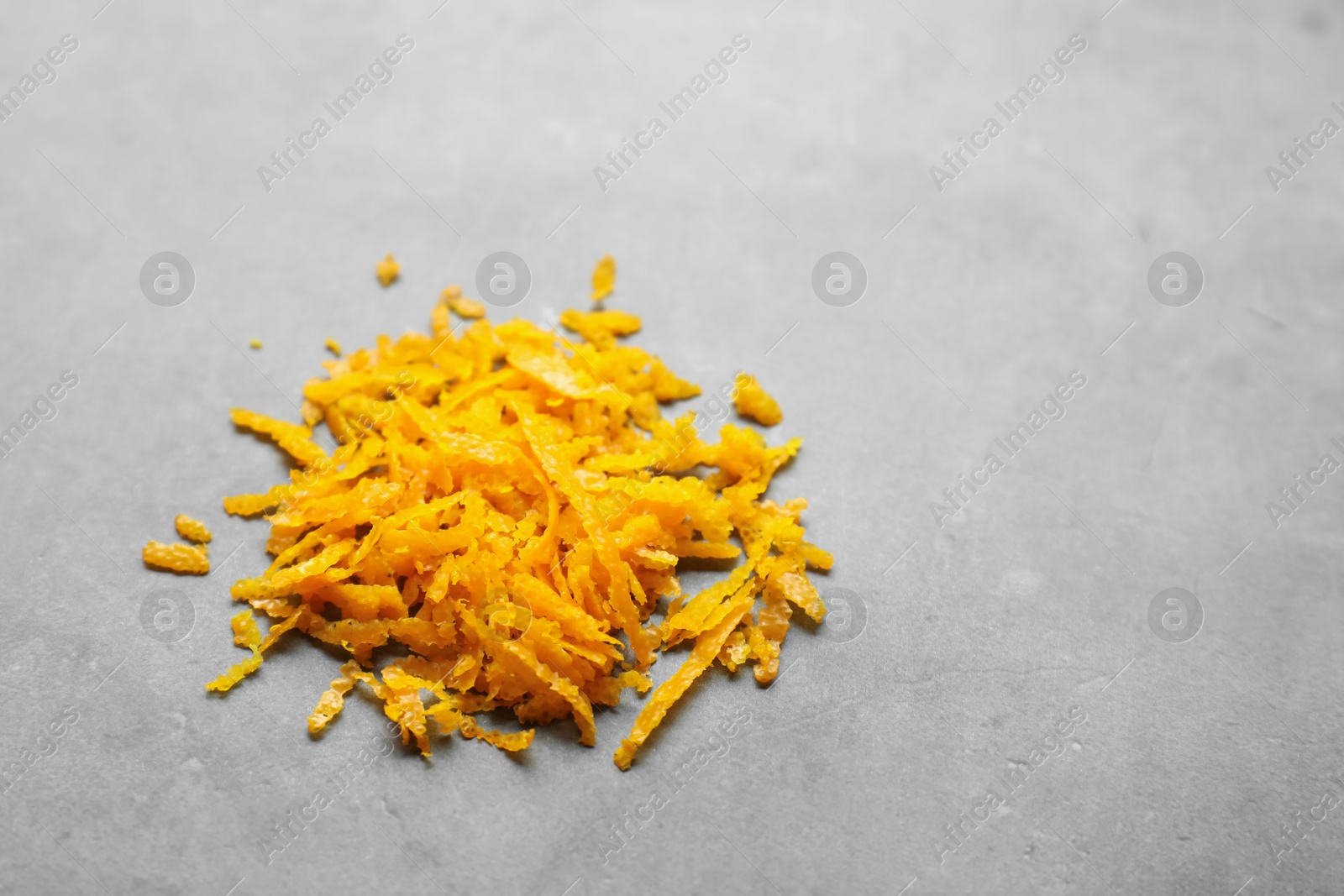 Photo of Pile of fresh orange zest on grey table, closeup. Space for text