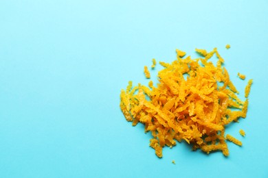 Photo of Pile of fresh orange zest on light blue background, top view. Space for text