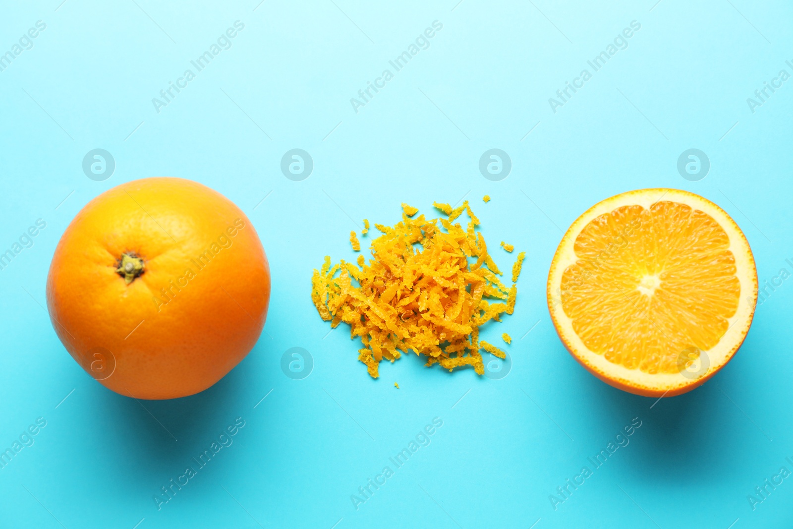 Photo of Pile of fresh orange zest, whole and cut fruits on light blue background, flat lay