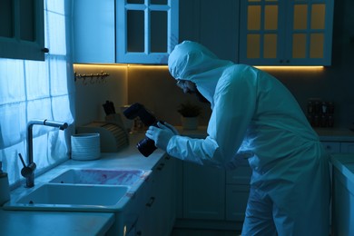 Photo of Forensic expert with camera working at crime scene indoors