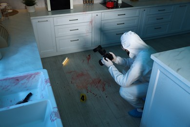 Photo of Forensic expert with camera working at crime scene indoors