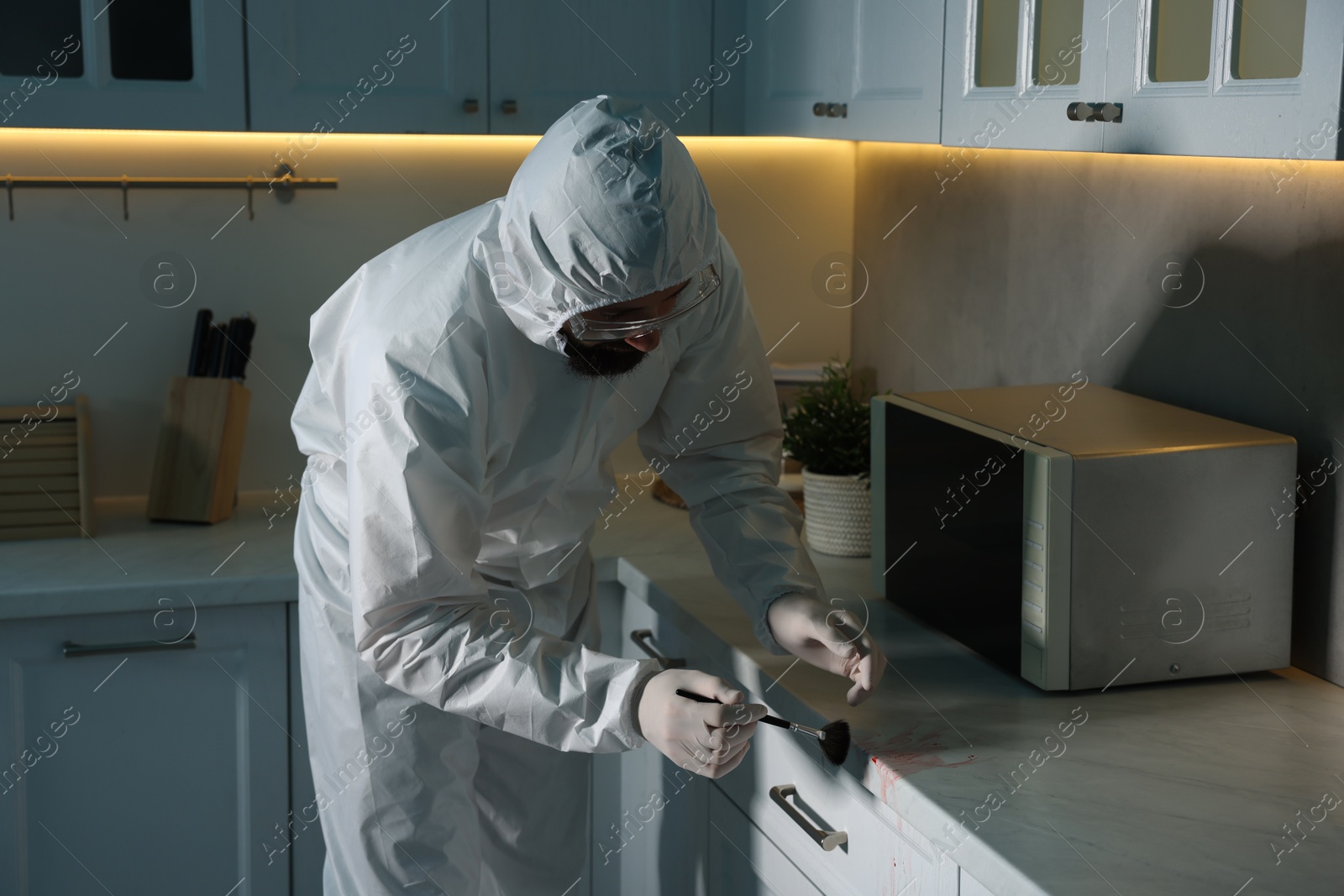 Photo of Forensic expert taking fingerprints from countertop with brush at crime scene indoors