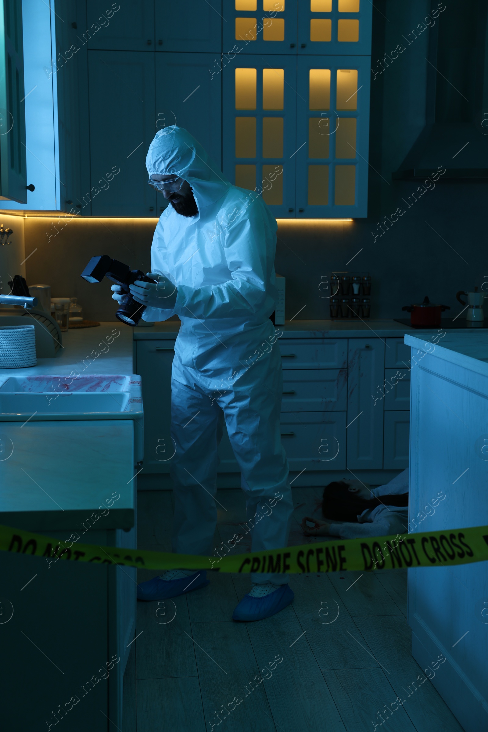 Photo of Forensic expert with camera working at crime scene in dark room