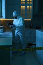 Photo of Forensic expert with camera working at crime scene in dark room