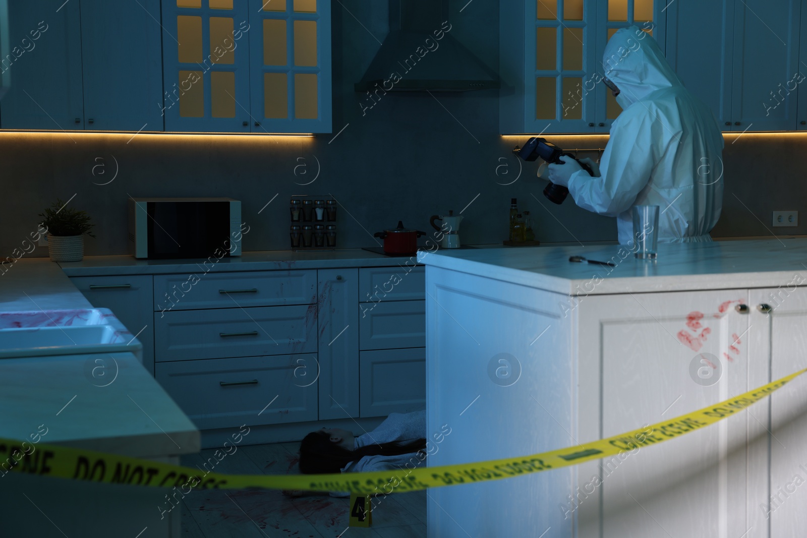 Photo of Forensic expert with camera working at crime scene in dark room