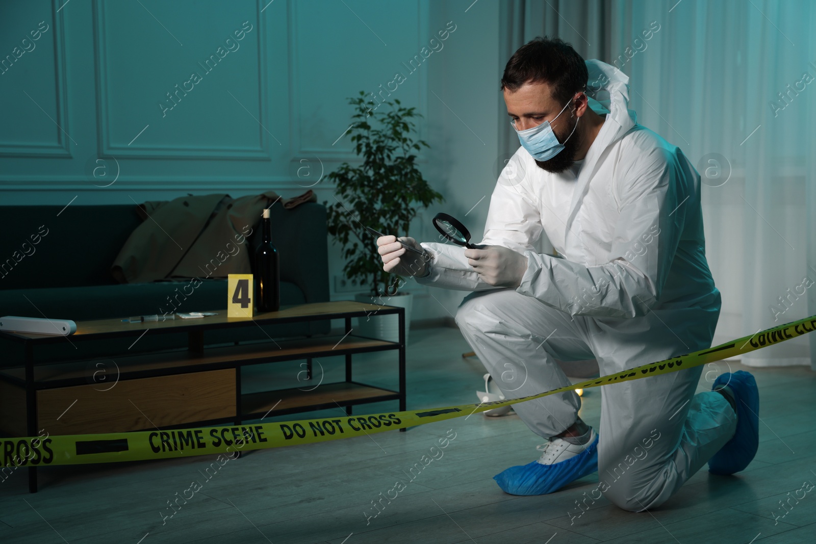 Photo of Forensic expert with tweezers examining hair through magnifying glass at crime scene indoors