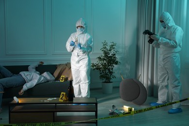 Photo of Forensic experts working at crime scene with dead woman's body indoors