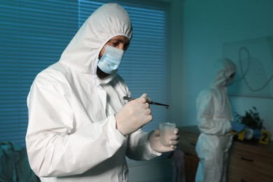 Forensic experts working at crime scene indoors