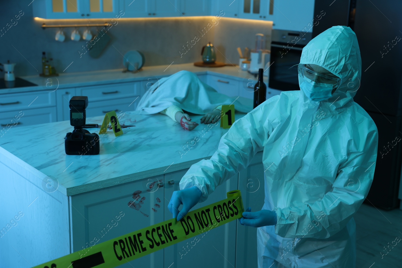 Photo of Forensic expert blocking way to crime scene and dead body with yellow tape indoors