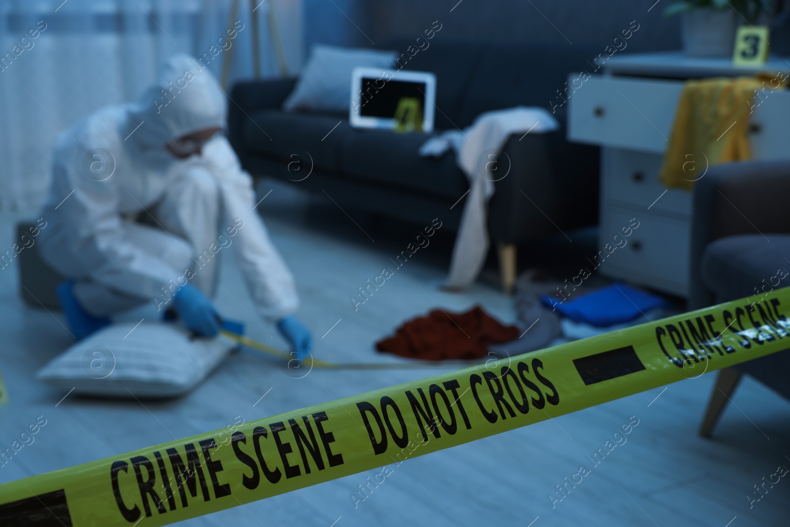 Photo of Forensic expert working at crime scene in messy room, focus on yellow tape