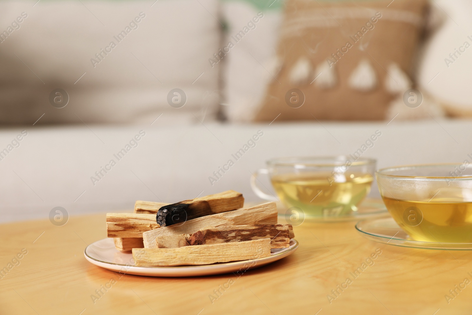 Photo of Palo santo sticks and tea on wooden table indoors