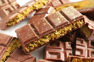 Photo of Pieces of tasty Dubai chocolate with pistachios and knafeh on white table, closeup