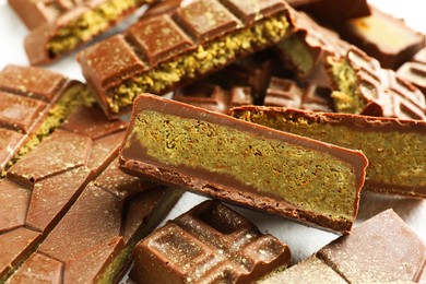 Photo of Pieces of tasty Dubai chocolate with pistachios and knafeh on white table, closeup