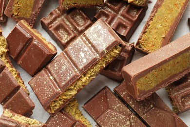 Photo of Pieces of tasty Dubai chocolate with pistachios and knafeh on white table, top view