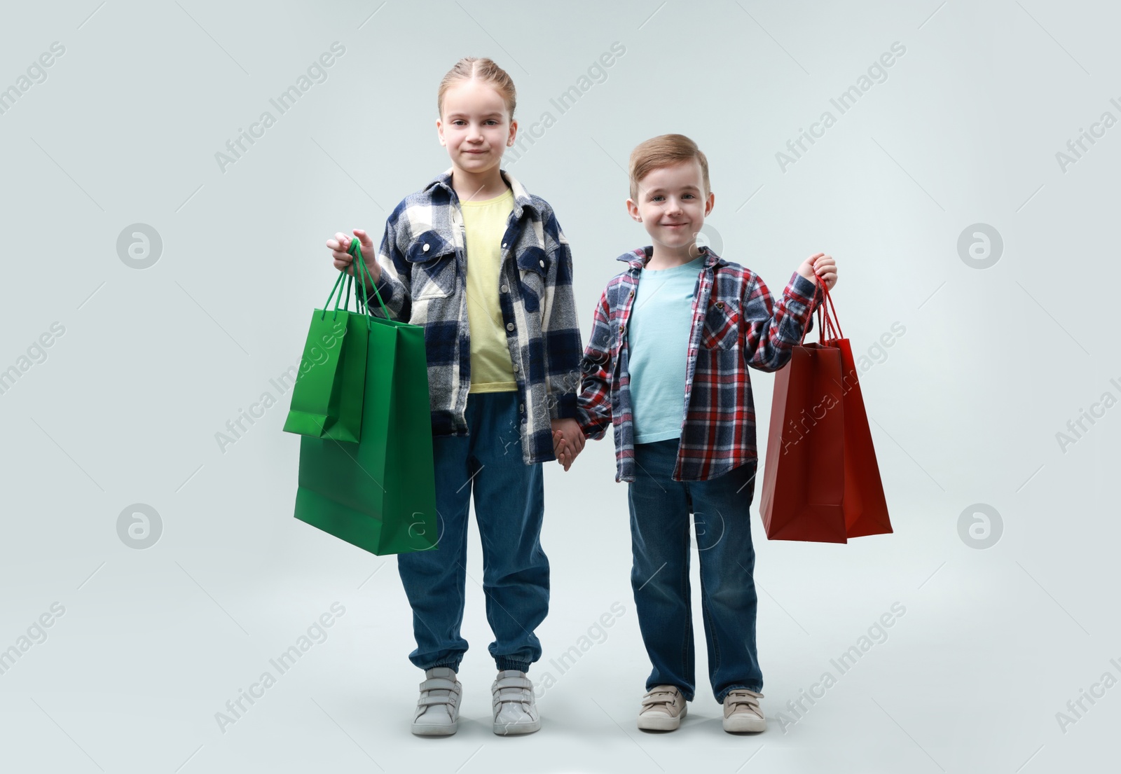 Photo of Cute little friends with shopping bags on grey background