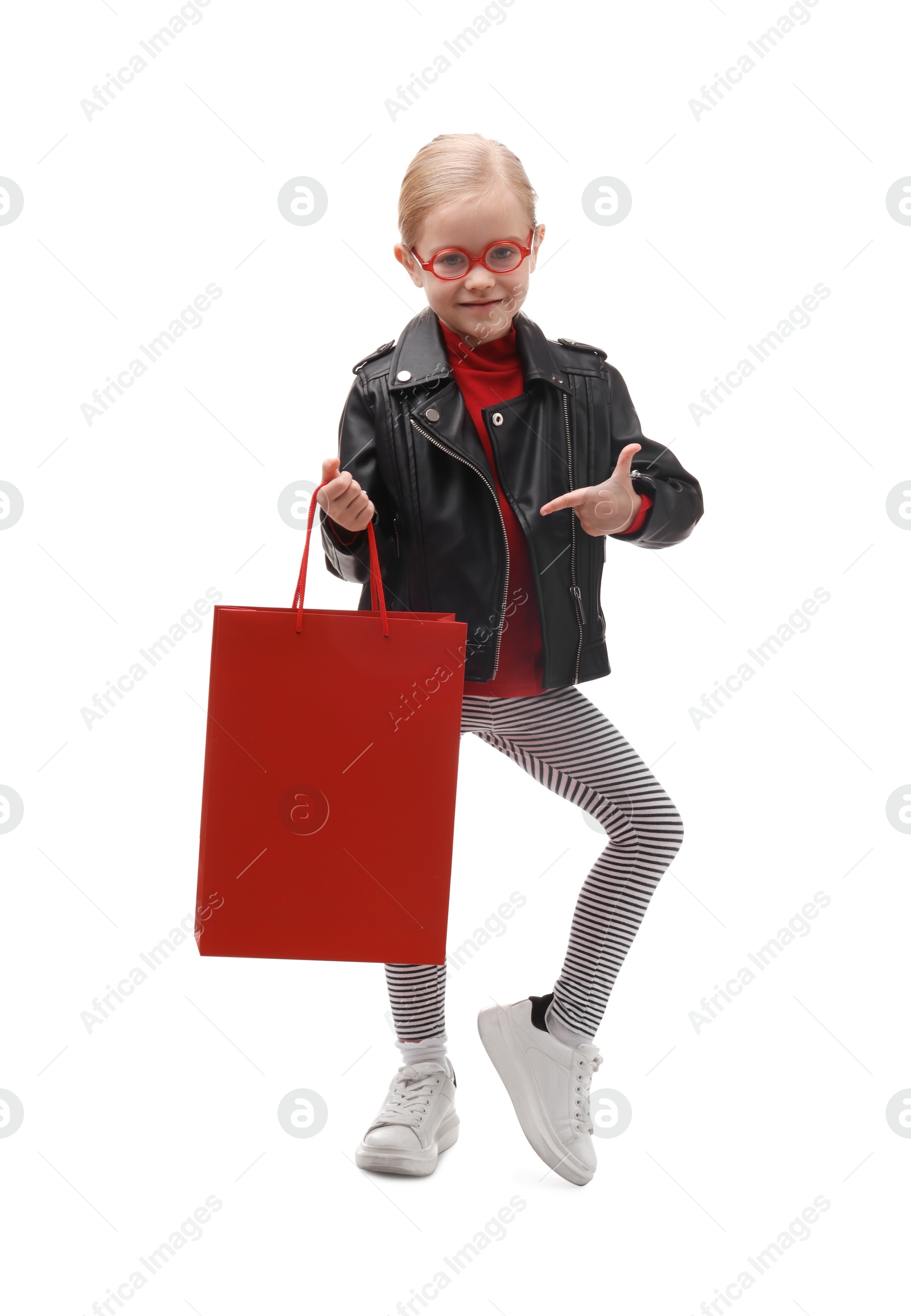 Photo of Little girl pointing at shopping bag on white background