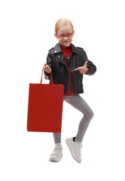 Little girl pointing at shopping bag on white background