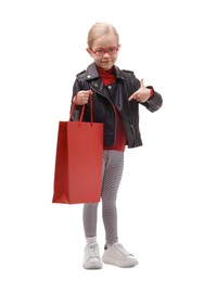 Photo of Little girl pointing at shopping bag on white background