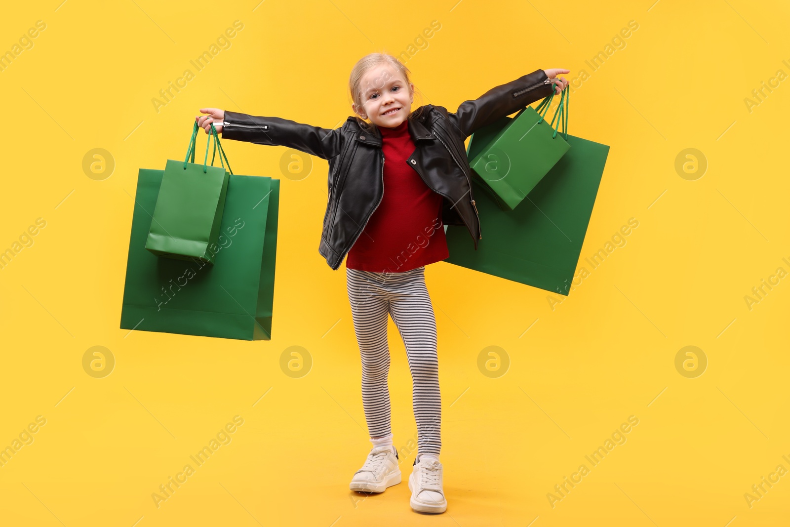 Photo of Little girl with shopping bags on orange background