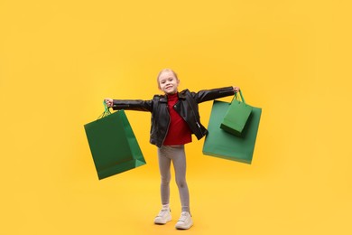 Photo of Little girl with shopping bags on orange background