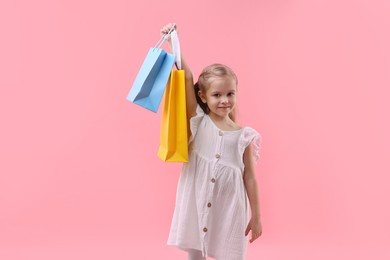 Photo of Little girl with shopping bags on pink background