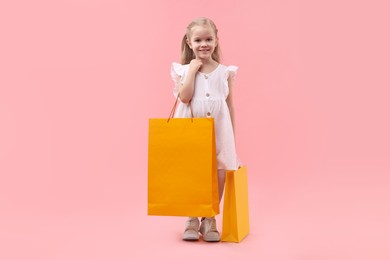 Photo of Little girl with shopping bags on pink background