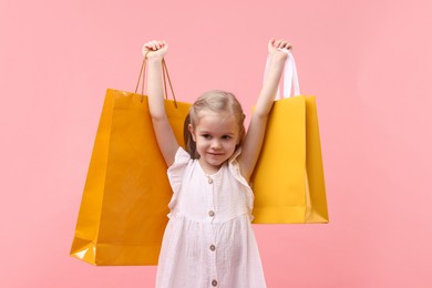 Photo of Little girl with shopping bags on pink background