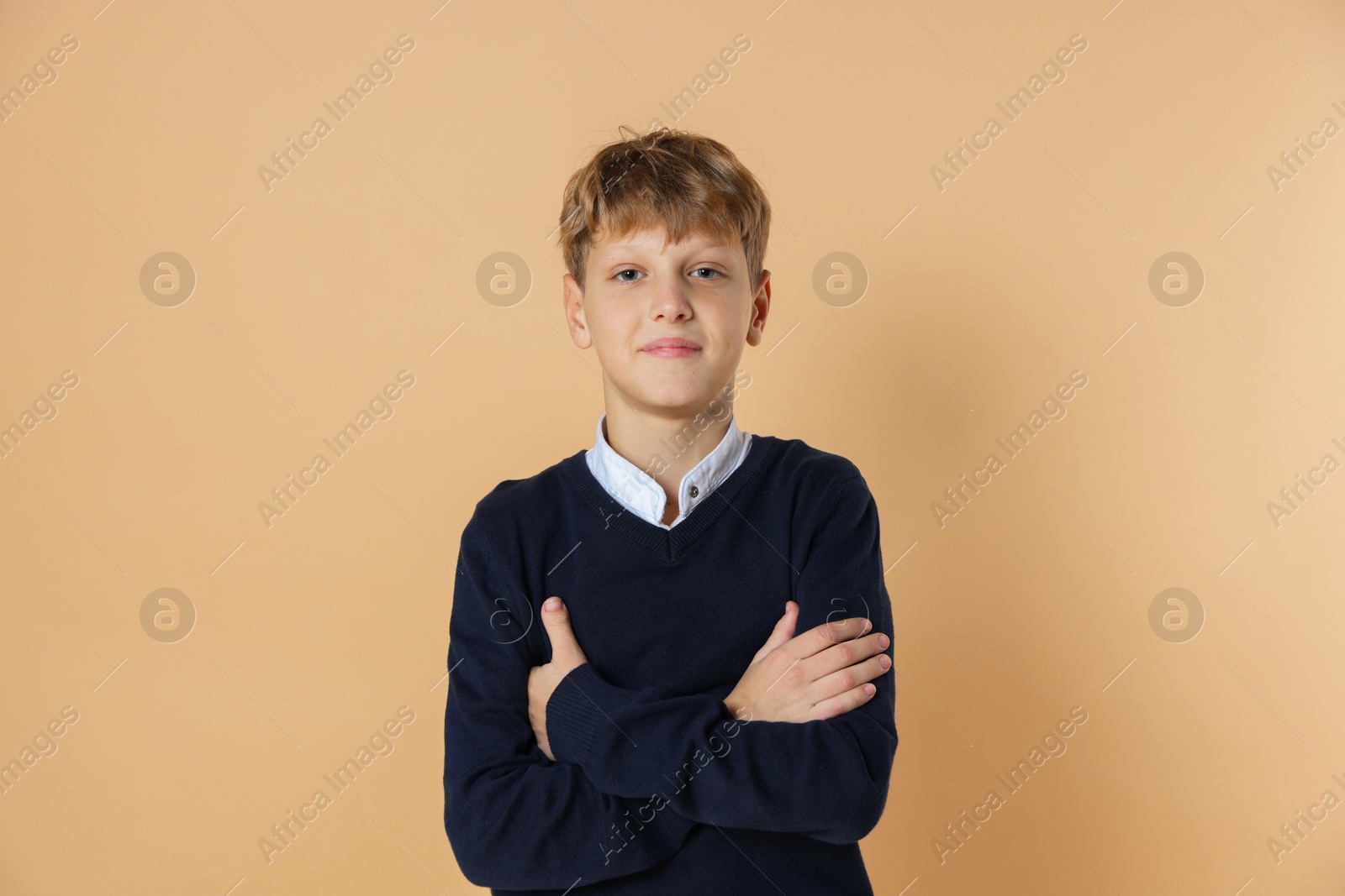 Photo of Portrait of teenage boy with crossed arms on beige background