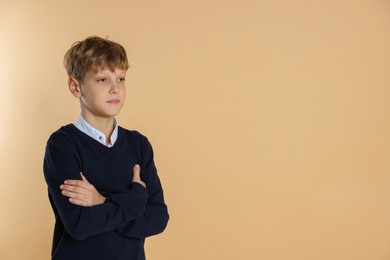 Photo of Portrait of teenage boy with crossed arms on beige background, space for text