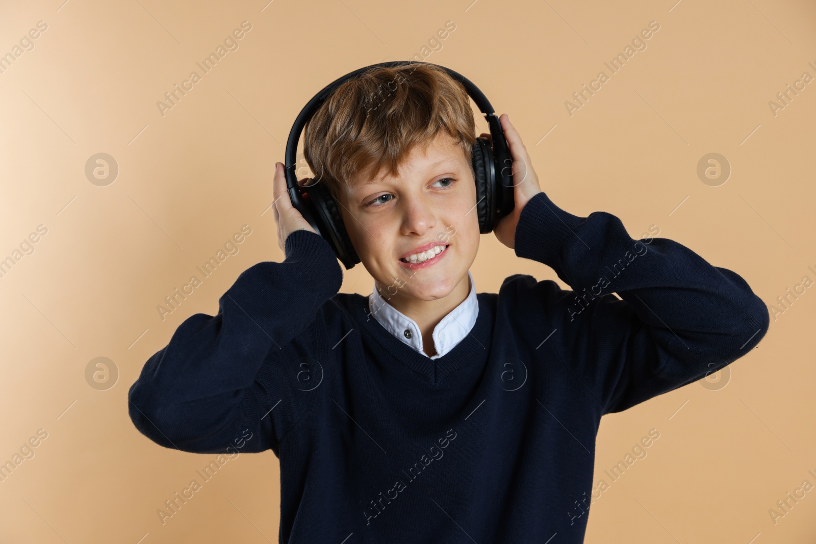 Photo of Portrait of teenage boy in headphones on beige background