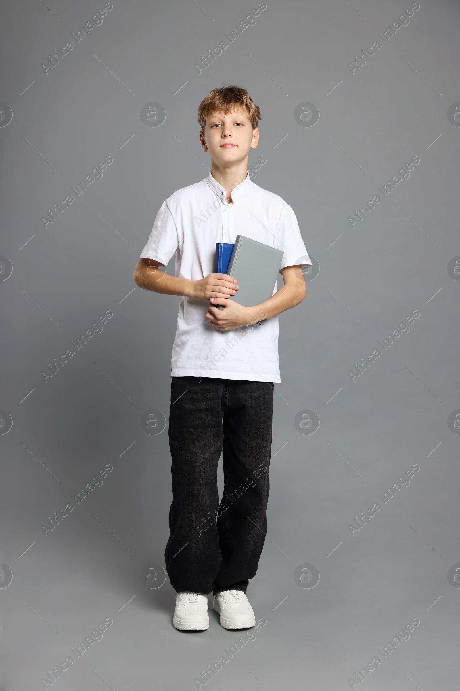 Photo of Full length portrait of teenage boy with books on grey background