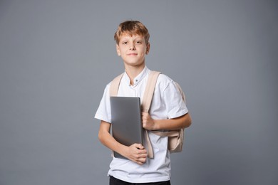 Photo of Portrait of teenage boy with laptop and backpack on grey background