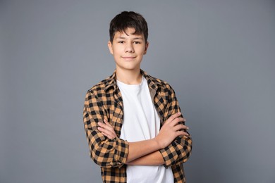 Photo of Portrait of teenage boy with crossed arms on grey background