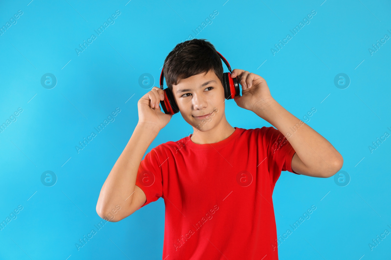 Photo of Portrait of teenage boy in headphones on light blue background