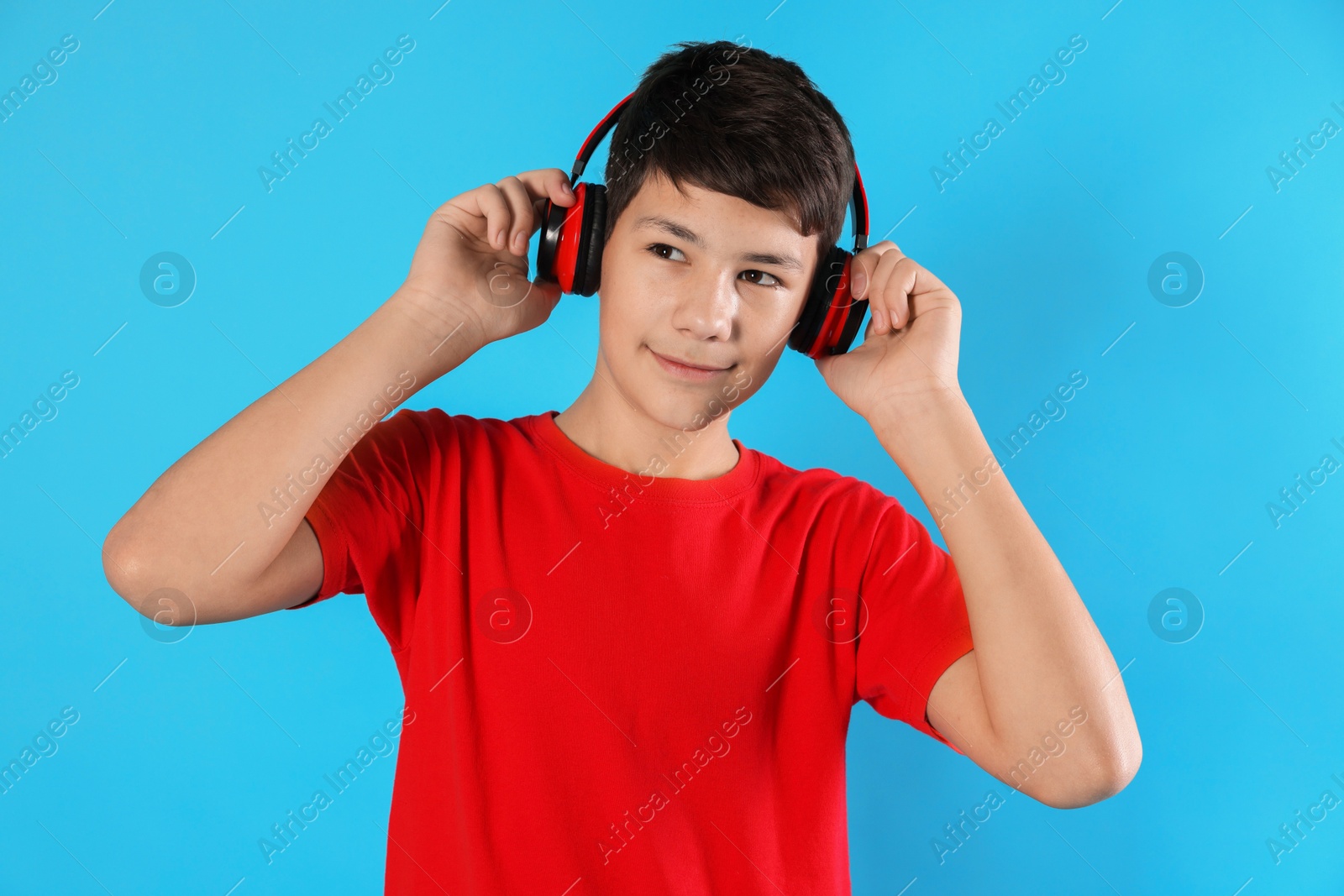 Photo of Portrait of teenage boy in headphones on light blue background