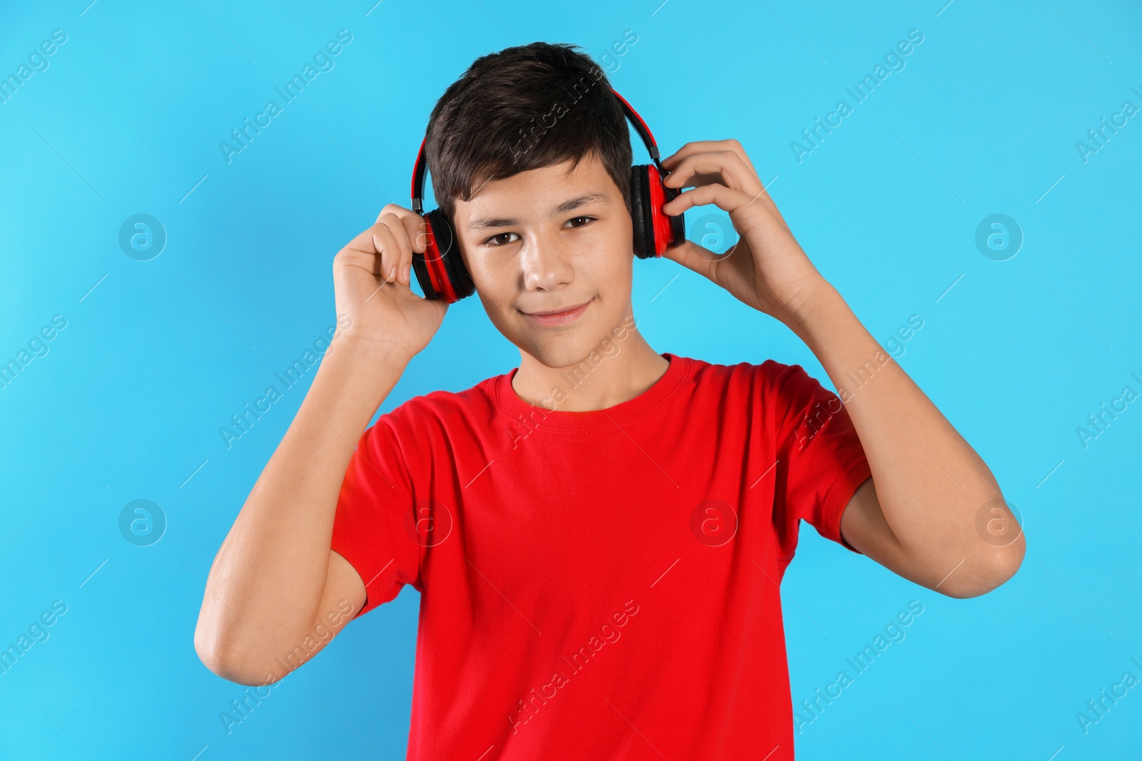 Photo of Portrait of teenage boy in headphones on light blue background