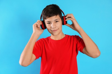 Photo of Portrait of teenage boy in headphones on light blue background