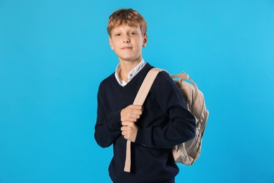 Photo of Portrait of teenage boy with backpack on light blue background