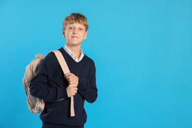 Photo of Portrait of teenage boy with backpack on light blue background, space for text