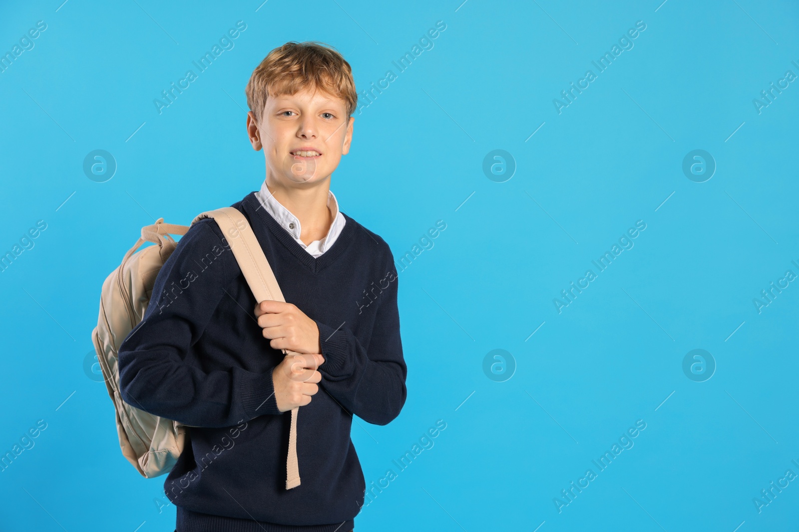 Photo of Portrait of teenage boy with backpack on light blue background, space for text