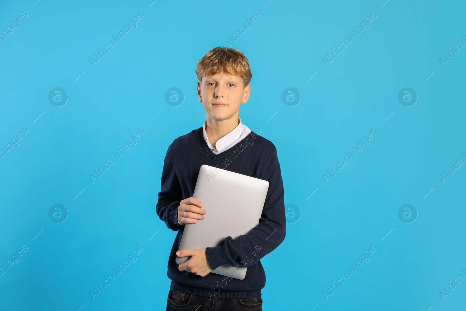 Photo of Portrait of teenage boy with laptop on light blue background