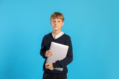 Photo of Portrait of teenage boy with laptop on light blue background