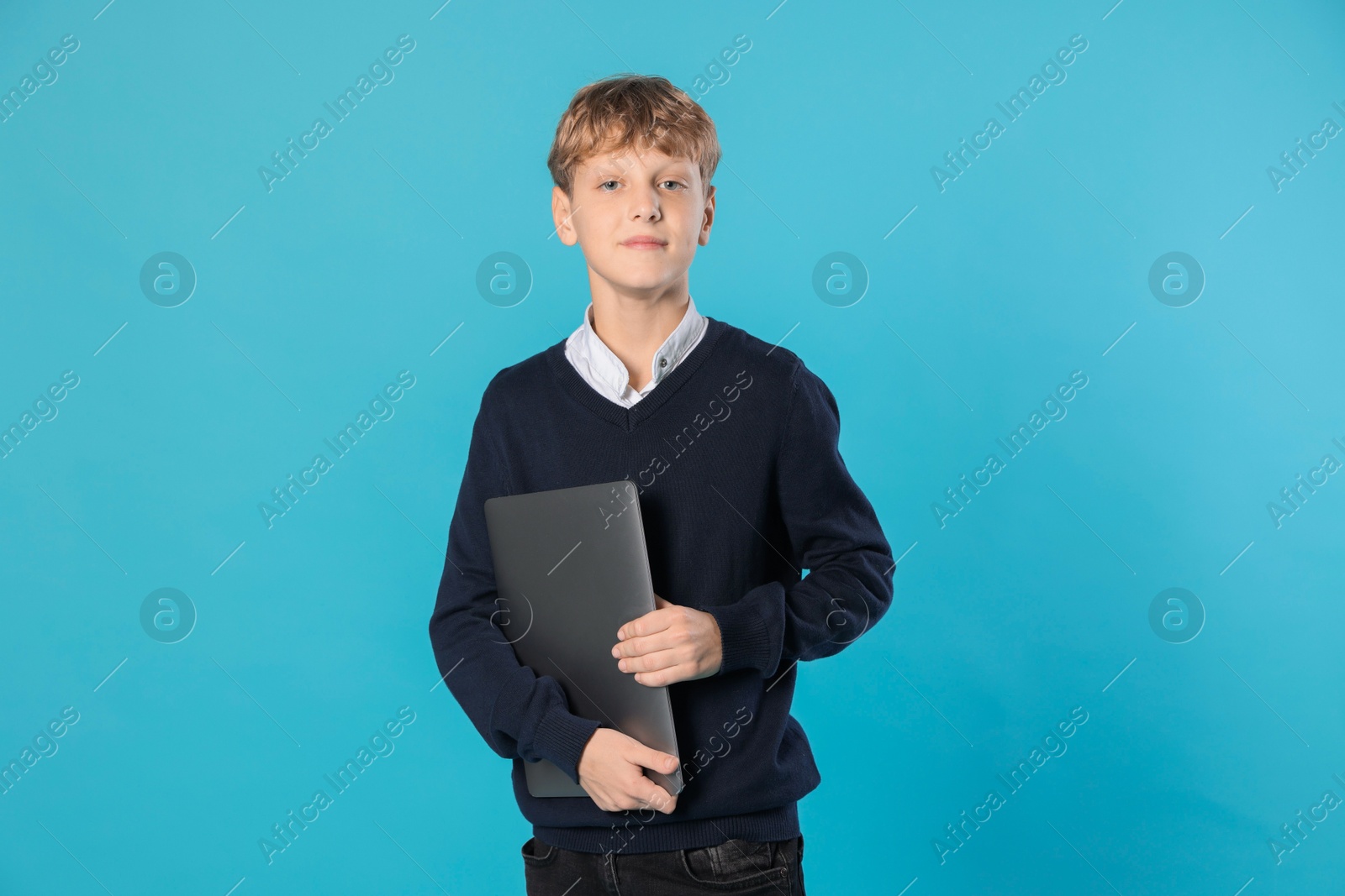 Photo of Portrait of teenage boy with laptop on light blue background