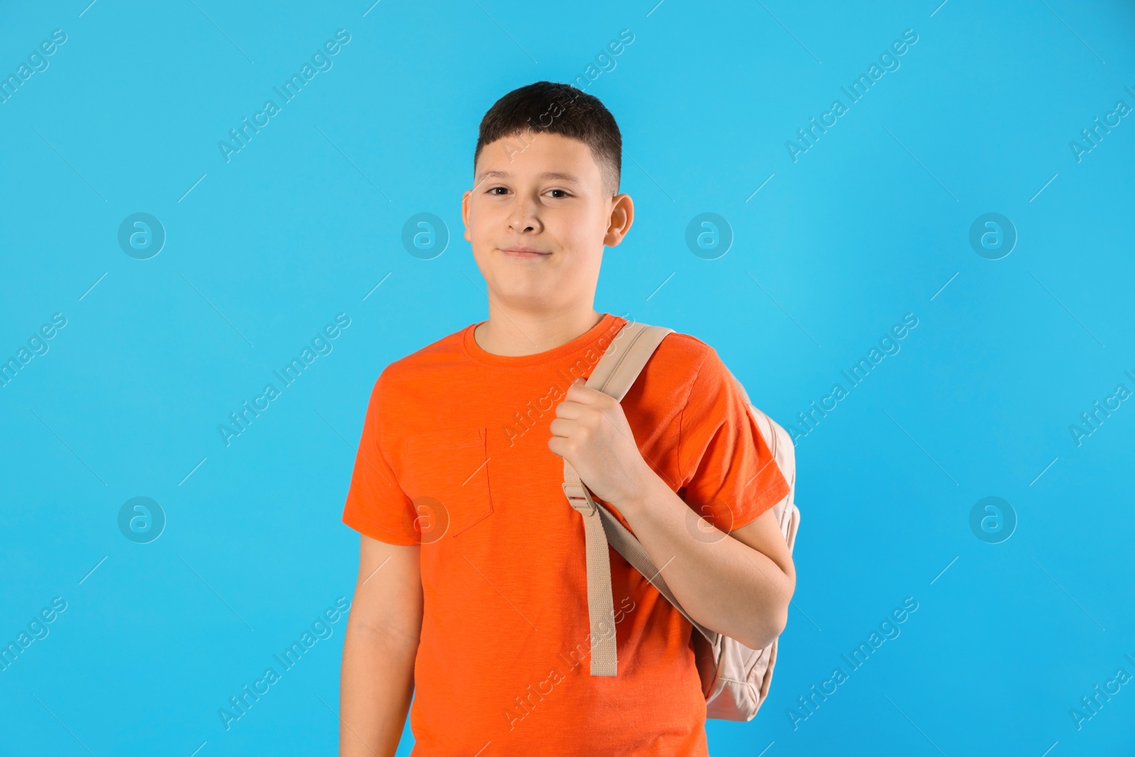 Photo of Portrait of teenage boy with backpack on light blue background