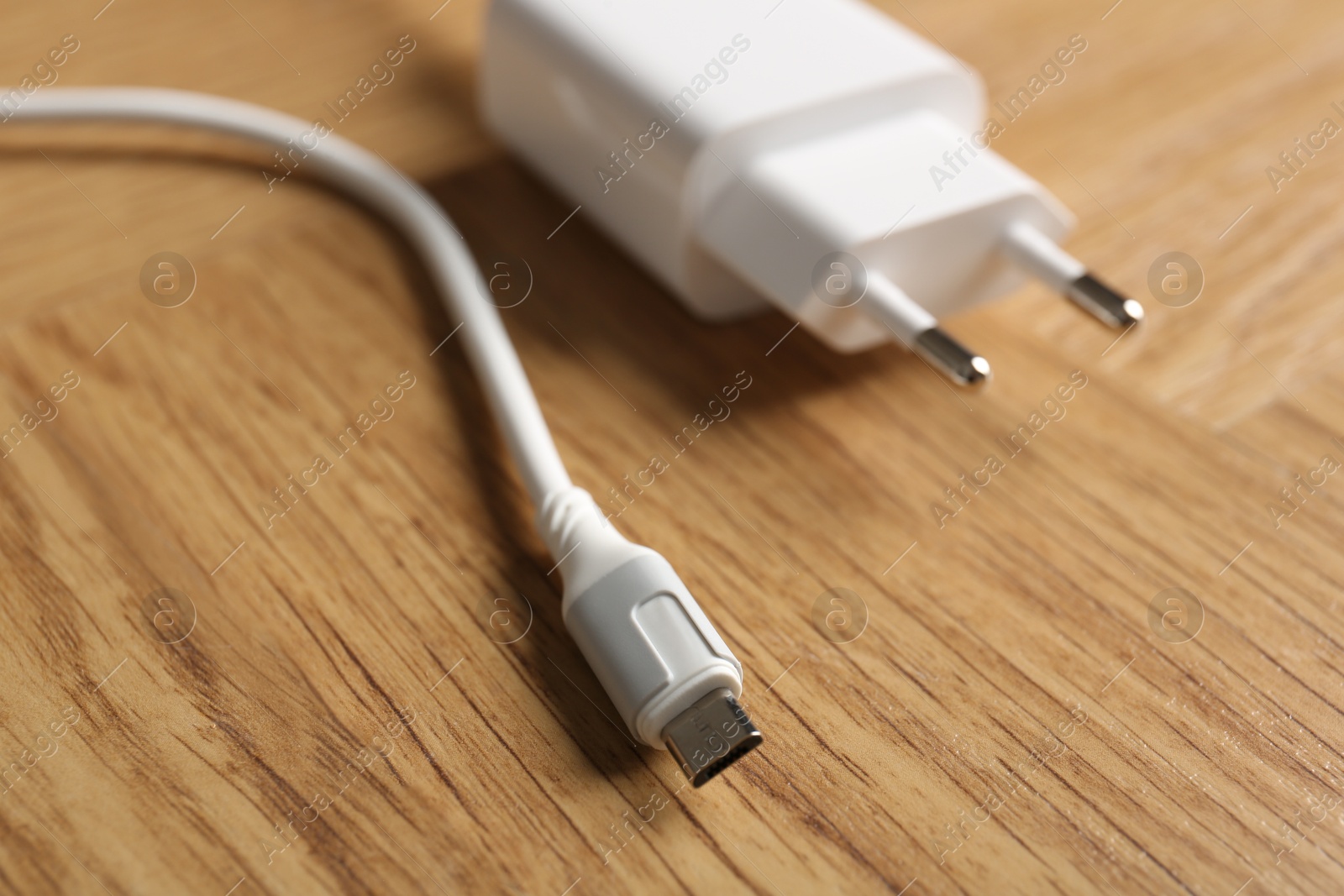 Photo of USB power adapter with charge cable on wooden table, closeup