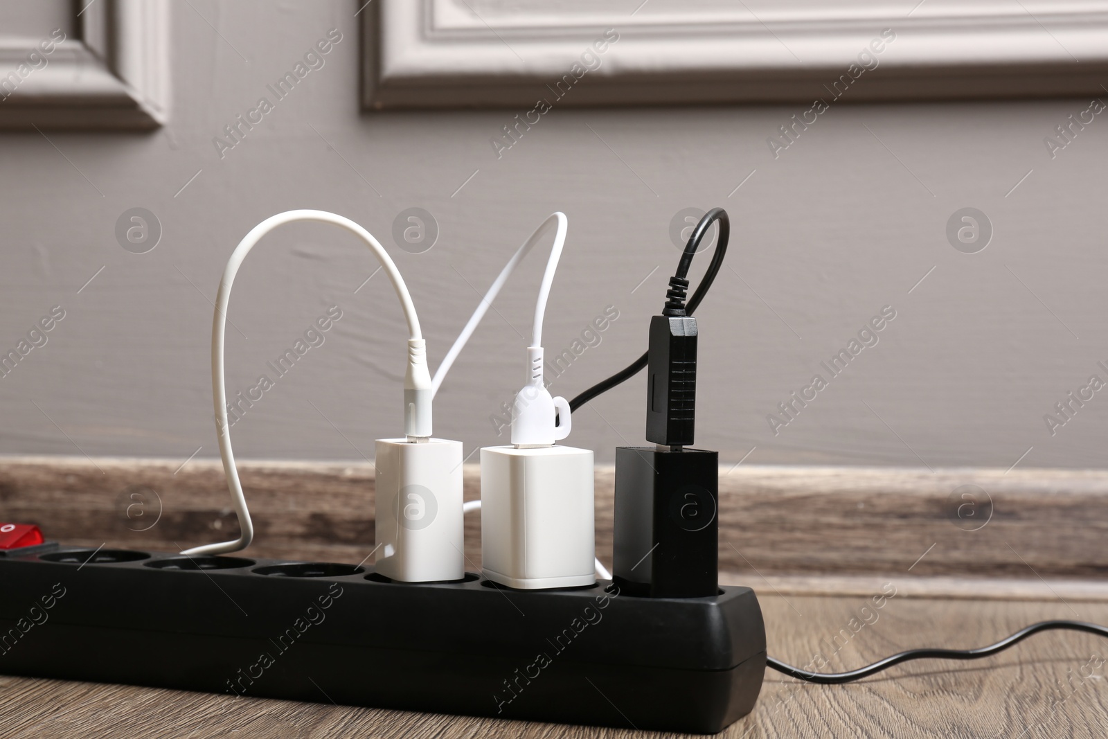 Photo of USB adapters with charge cables in power strip on floor indoors, closeup