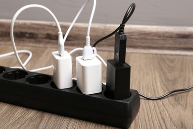 Photo of USB adapters with charge cables in power strip on floor indoors, closeup