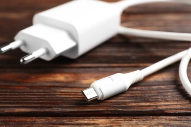 Photo of USB power adapter with charge cable on wooden table, closeup