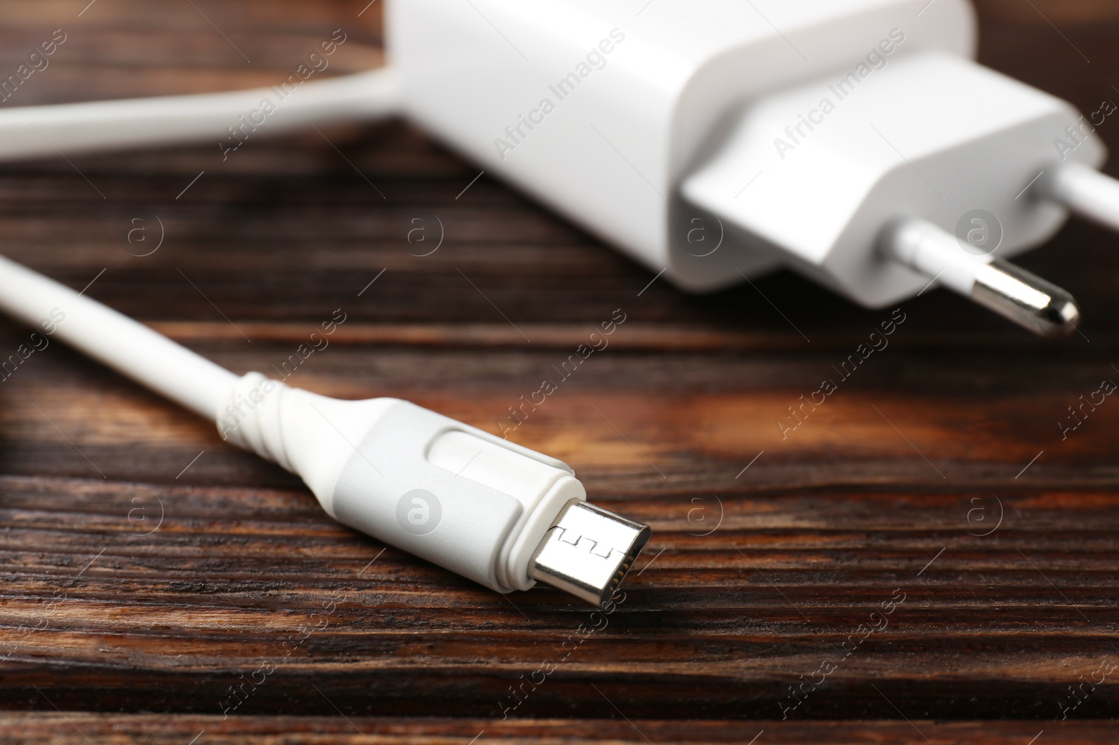 Photo of USB power adapter with charge cable on wooden table, closeup