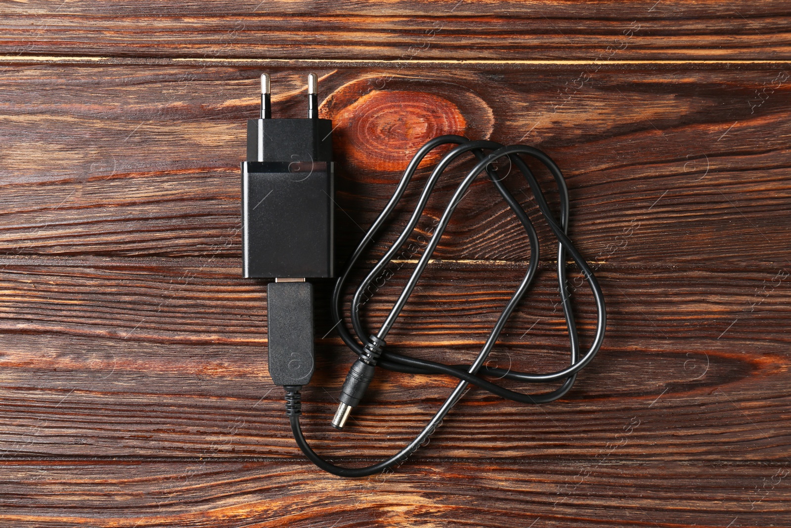 Photo of USB power adapter with charge cable on wooden table, top view